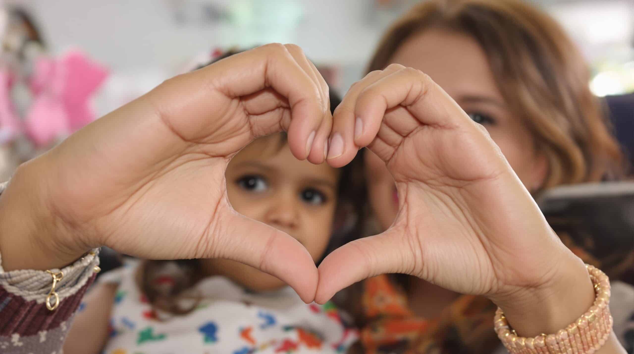 A woman and her daughter form a heart with their hands