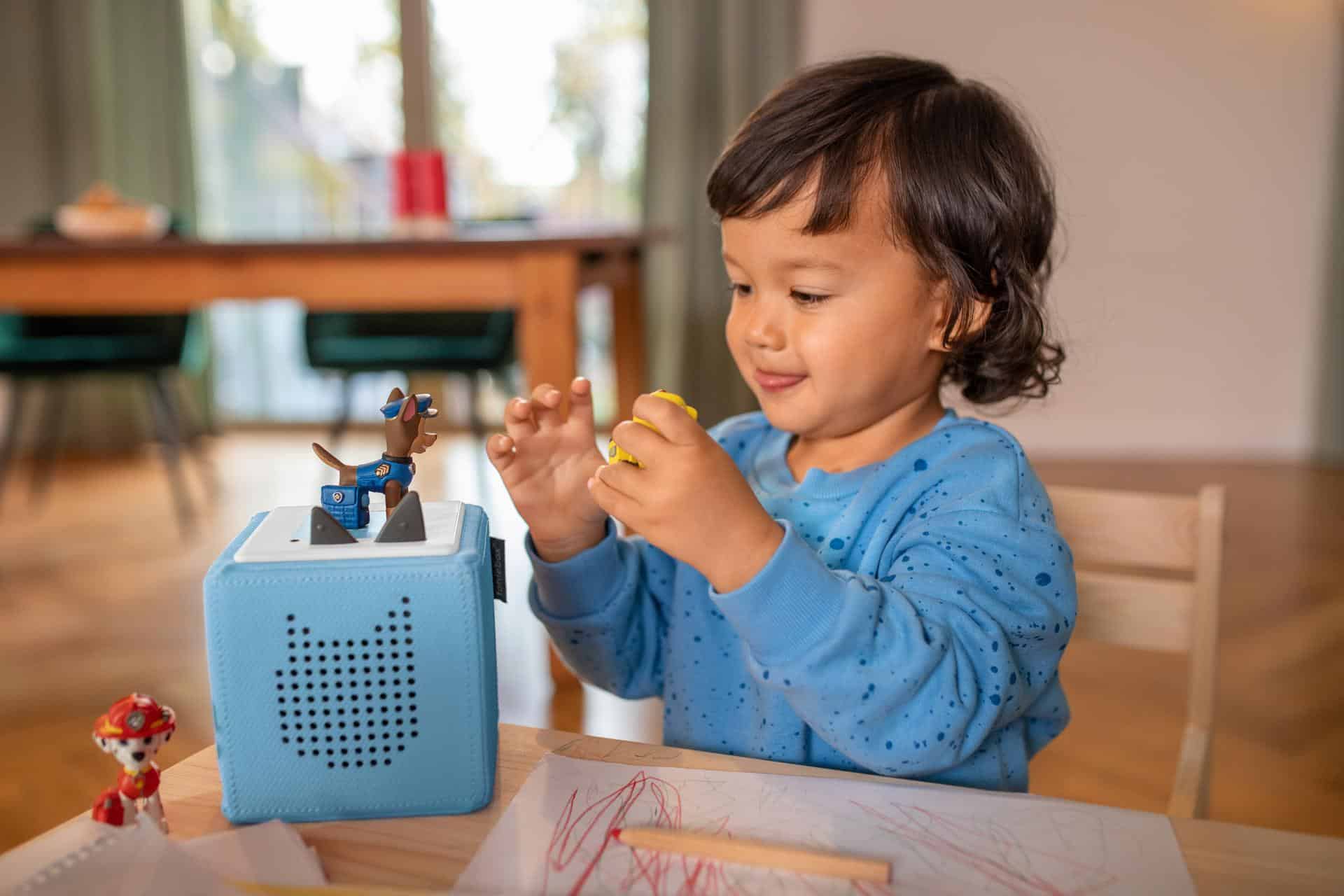 A young boy listens to a Tonie in the dining room.