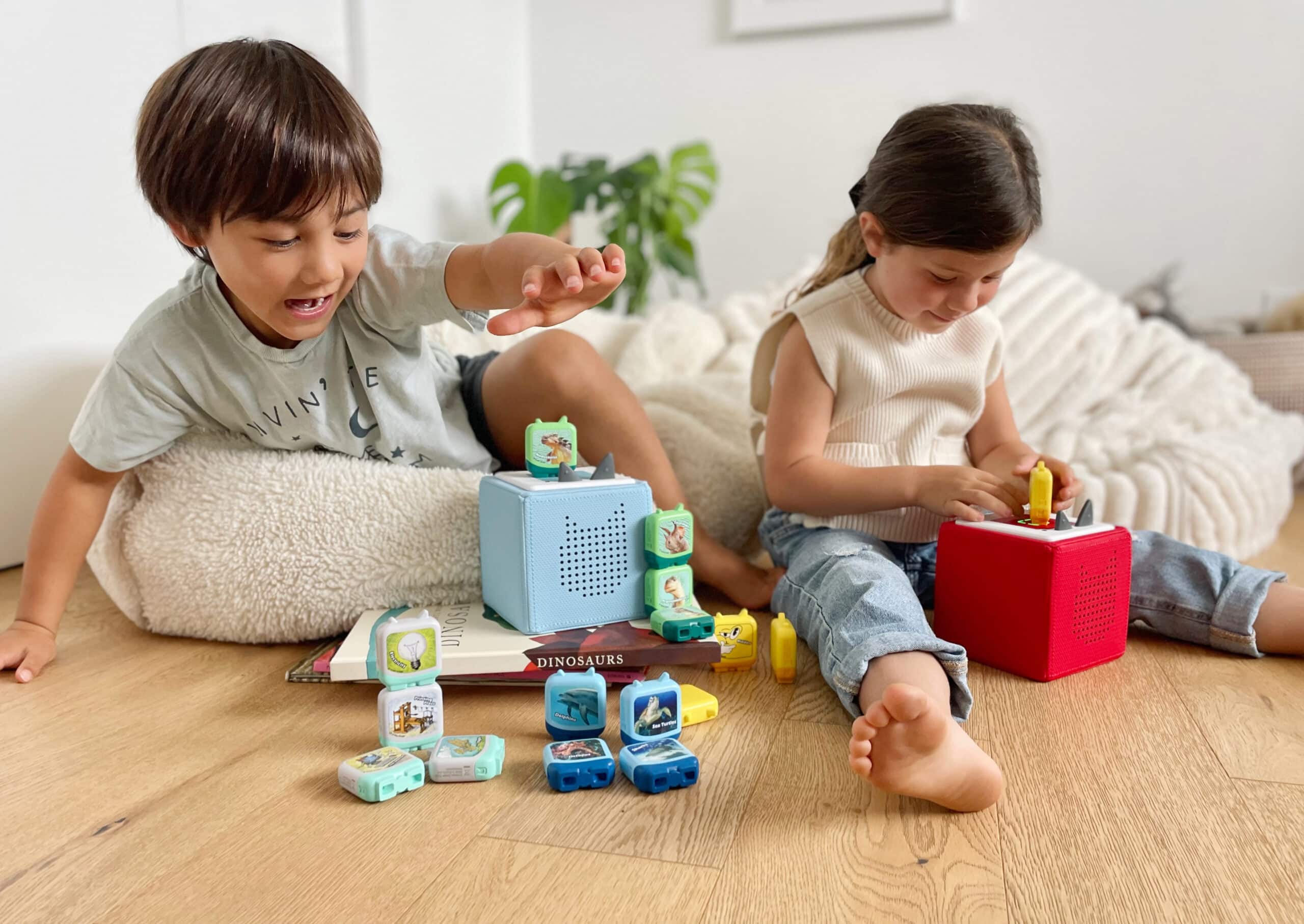 Two children are sitting in a nursery listening to Tonies on their Tonieboxes.